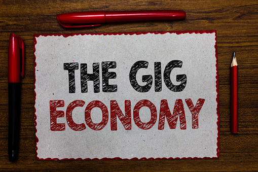 Text sign showing The Gig Economy. Conceptual photo Market of Short-term contracts freelance work temporary Red bordered white page centered some texts wooden desk pen pencil