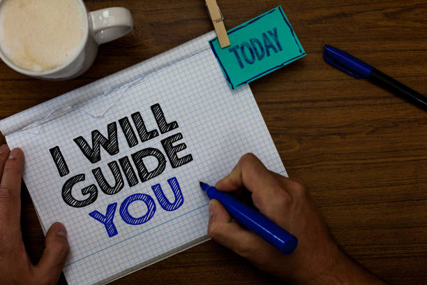 istock Writing note showing I Will Guide You. Business photo showcasing Help showing a route Influence to do or think something Hand hold pen coffee cup blue pen paper clip stick on woody table. 1046620320