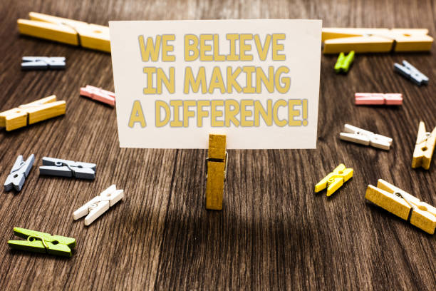 istock Text sign showing We Believe In Making A Difference. Conceptual photo self-confidence that can be unique Clothespin holding white paper note several clothespins wooden floor. 1046623022