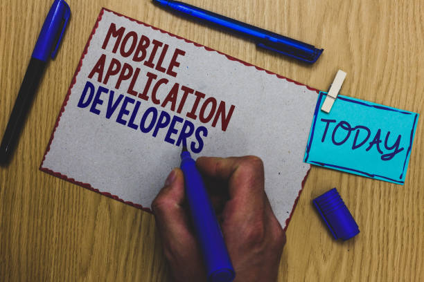 istock Conceptual hand writing showing Mobile Application Developers. Business photo text create software for devices like Android Man holding marker paper clothespin express ideas wooden table. 1046623408