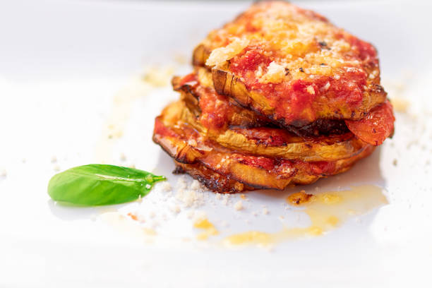 parmigiana di melanzane. tradicional plato italiano: cocido al horno las berenjenas a la parmesana, decorado con albahaca fresca. - berenjena fotografías e imágenes de stock