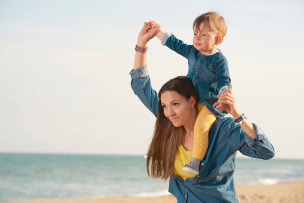 istock mother walking on beach with her daughter 1046628086