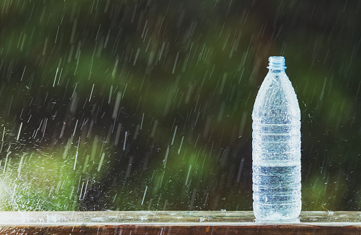 Heavy rain fills a water bottle.