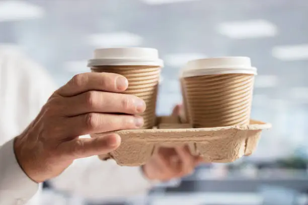 Photo of Businessman carrying coffee take out disposable cups in office for meeting
