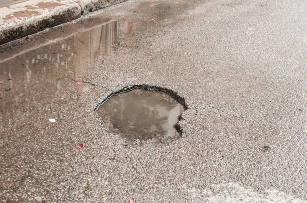 istock Pothole with puddle on asphalt road 1046630958