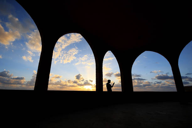 Silhouette of a man tking a selfie among arches during sunset in Batroun, Lebanon.