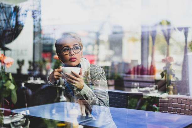 istock Young asian female drinking coffee and looking through window. 1046634858