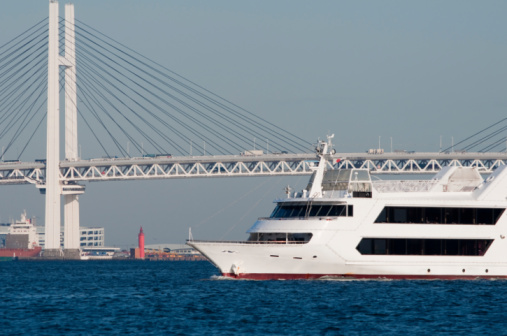 A passenger ship passing by the Yokohama Bay Bridge. in Yokohama, Japan. Cruising in the bay is one of the most famous tourist attractions in Yokohama. 
