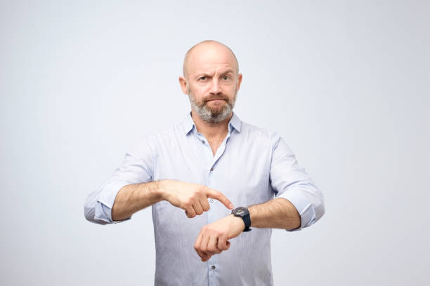 Mature european businessman impatiently pointing to his watch. Why are you late concept. stock photo