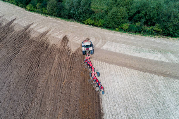 istock Tractor harrownig the large brown field 1046643218