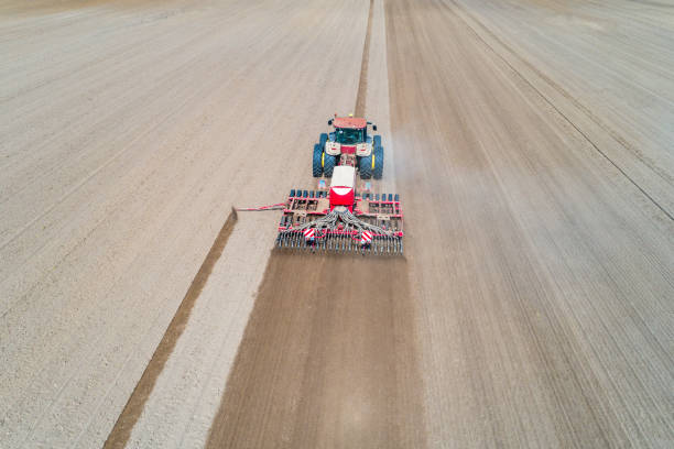 istock Tractor harrownig the large brown field 1046643604