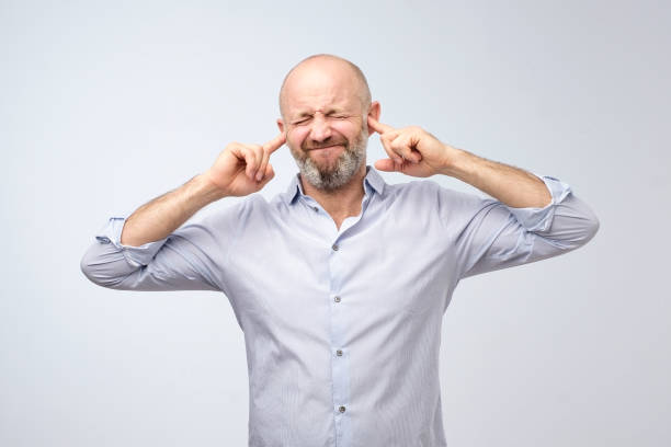 istock Annoyed mature man plugging ears with fingers 1046646144
