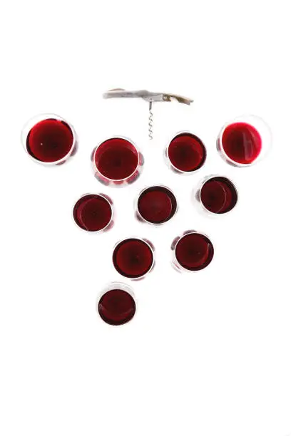 beautiful still life composition with red wine glasses disposed in a bunch of grapes shape with a corkscrew for branch, on a absolute white background