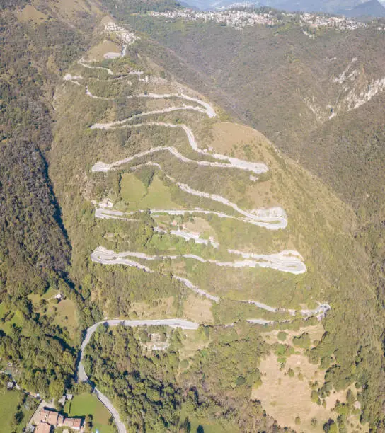 Photo of Drone aerial view of the mountain road in Italy that connects the village of Nebro to Selvino. Amazing aerial view of the mountain bends creating beautiful shapes
