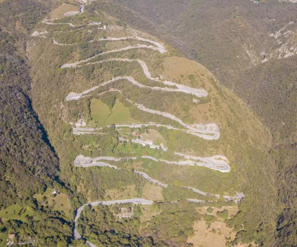 Photo of Drone aerial view of the mountain road in Italy that connects the village of Nebro to Selvino. Amazing aerial view of the mountain bends creating beautiful shapes