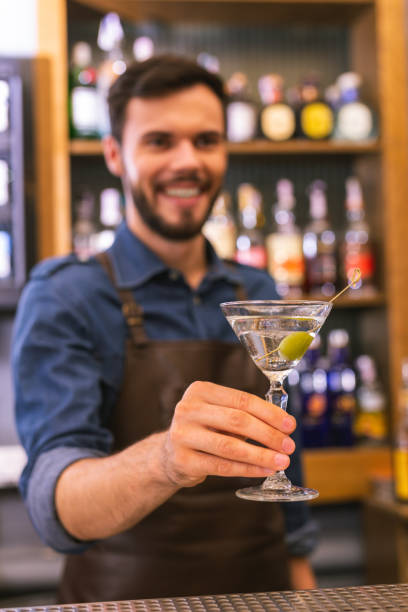 istock Positive barman smiling while offering cold alcohol drink 1046688302