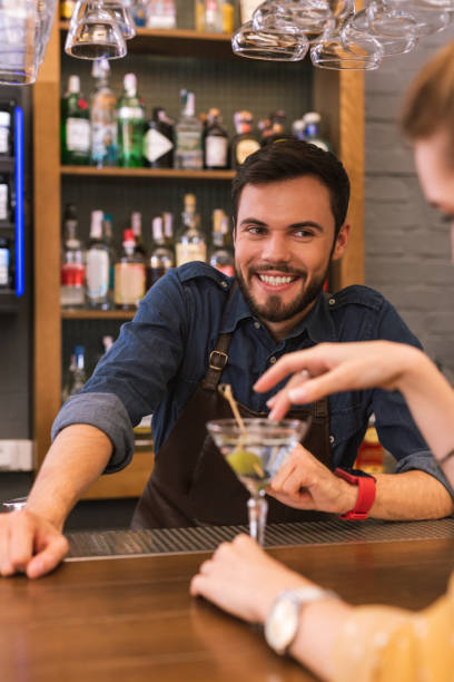 istock Handsome barman smiling and flirting with young visitor 1046688380