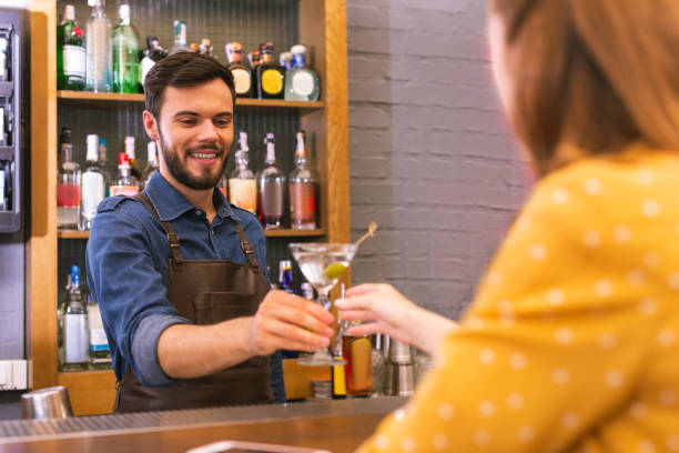 istock Happy barman smiling to the visitor while giving her alcohol 1046688396