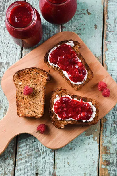 Tasty summer breakfast. Homemade berry jam on ciabatta toasts on old shabby blue boards overhead view