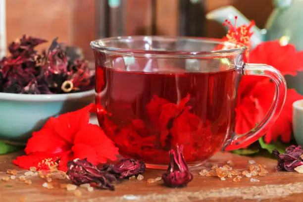 Photo of Red karkade hibiscus red sorrel tea in glass mug with dry tea cu