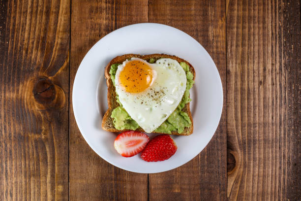 тост с авокадо и яйцом в форме сердца - breakfast plate стоковые фото и изображения