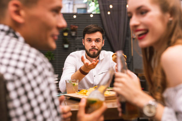 istock Offended young man looking at his friends while eating burgers 1046694176