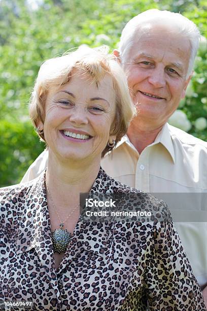 Foto de Sorrindo Casal De Idosos No Jardim Exuberante e mais fotos de stock de 60 Anos - 60 Anos, 70 anos, Abraçar