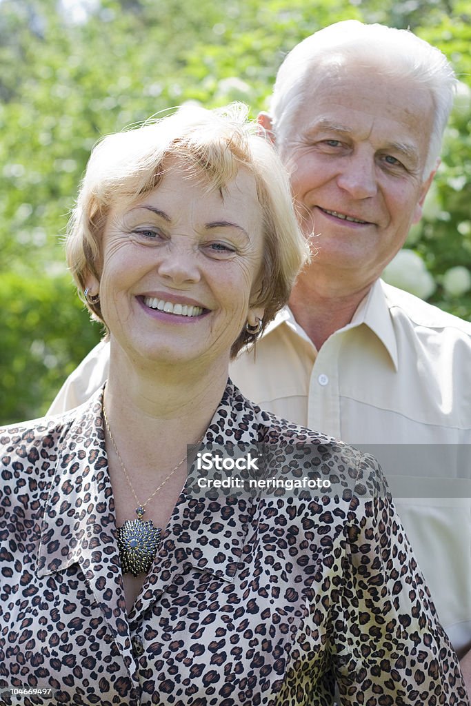Портрет улыбающегося старшего пара в цветущий сад - Стоковые фото 60-69 лет роялти-фри