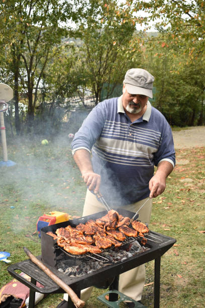 istock Man preparing barbecue outdoors for family. 1046703074