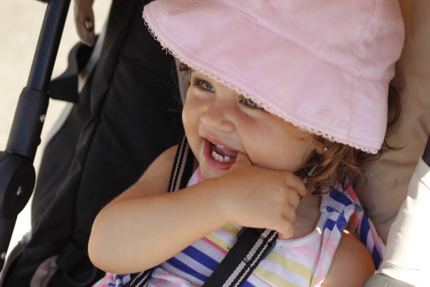 Close up of a toddler sitting in her pram happy with a very happy facial expression.