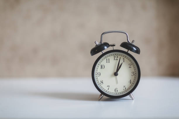 istock alarm clock on white table and brown background 1046764914