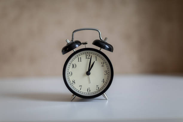 istock alarm clock on white table and brown background 1046764918