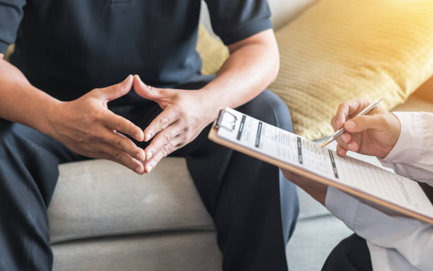 paciente do sexo masculino ter consulta com o médico ou psiquiatra que trabalhando no exame diagnóstico na doença de saúde ou doença mental dos homens em médico centro de serviços de saúde mental de clínica ou hospital - mental illness audio - fotografias e filmes do acervo