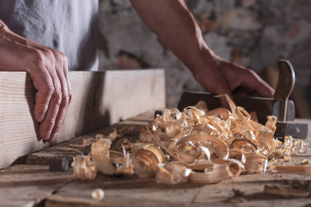 istock Man scraping curled wood scraps with hand plane tool 1046787342