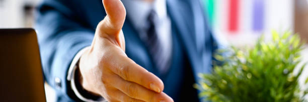 istock Man in suit and tie give hand as hello in office 1046788102