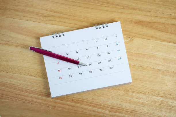 istock Calendar page with pen on wooden desk table 1046812434