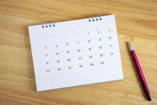 istock Calendar page with pen on wooden desk table 1046812438