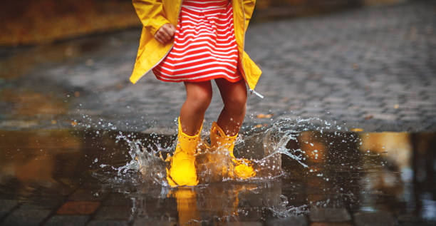 leg of child in rubber boots in puddle  on autumn walk happy child in yellow rubber boots  in puddle on an autumn walk puddle stock pictures, royalty-free photos & images