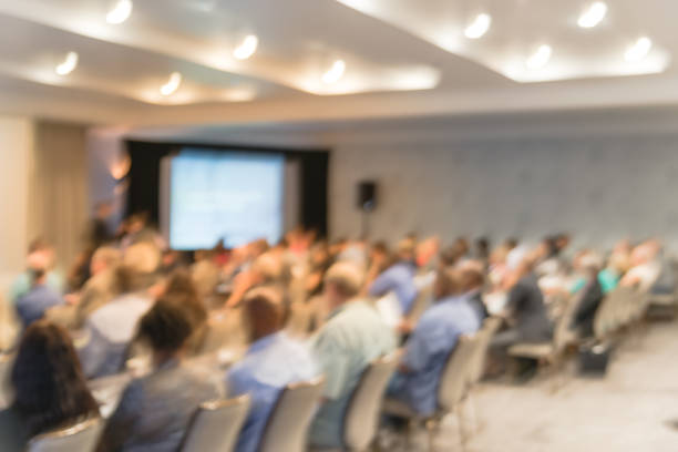 istock Blurry background speaker on conference stage with projector in America 1046832538
