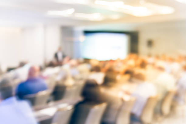 istock Blurry background speaker on conference stage with projector in America 1046832836