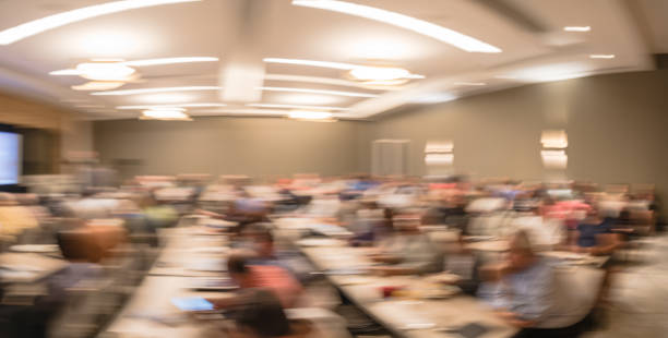 istock Panoramic blurry background speaker on conference stage with projector in USA 1046835232