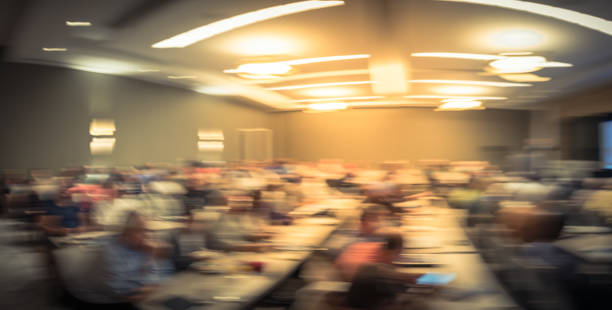 istock Panoramic blurry background speaker on conference stage with projector in USA 1046835262