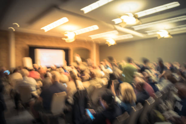 istock Blurry background speaker on conference stage with projector in America 1046835490