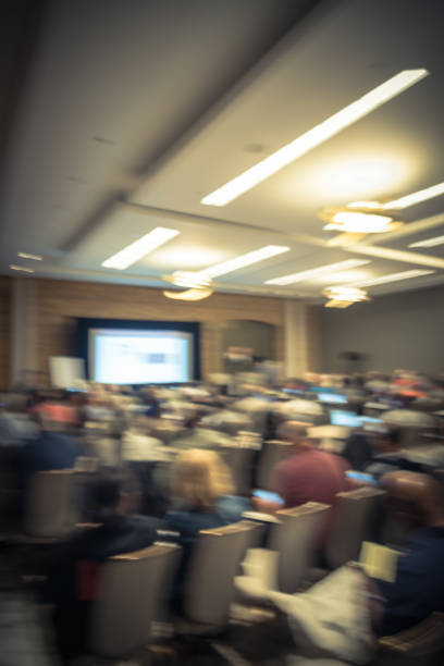 istock Filtered tone blurry background speaker on conference stage with projector in USA 1046835536