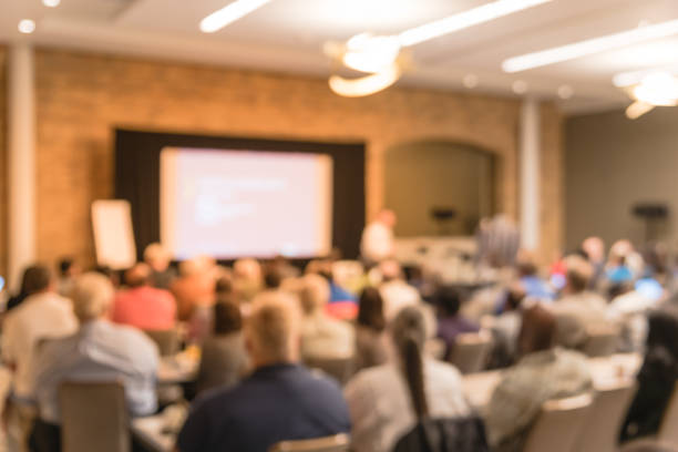 istock Blurry background speaker on conference stage with projector in America 1046835642