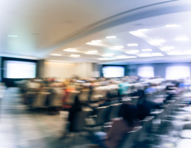 istock Panoramic blurry background speaker on conference stage with projector in USA 1046835834
