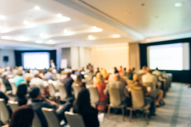 istock Blurry background speaker on conference stage with dual projectors in USA 1046835882