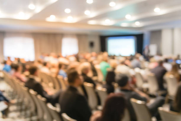 istock Blurry background speaker on conference stage with projector in America 1046837934