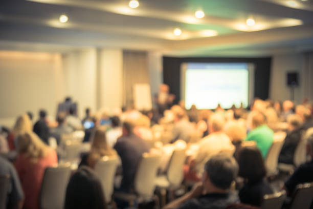 istock Blurry background speaker on conference stage with projector in America 1046837948