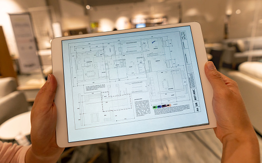 Close-up on a person looking at a blueprint at a furniture store - housing project. **DESIGN ON SCREEN WAS MADE FROM SCRATCH BY US**